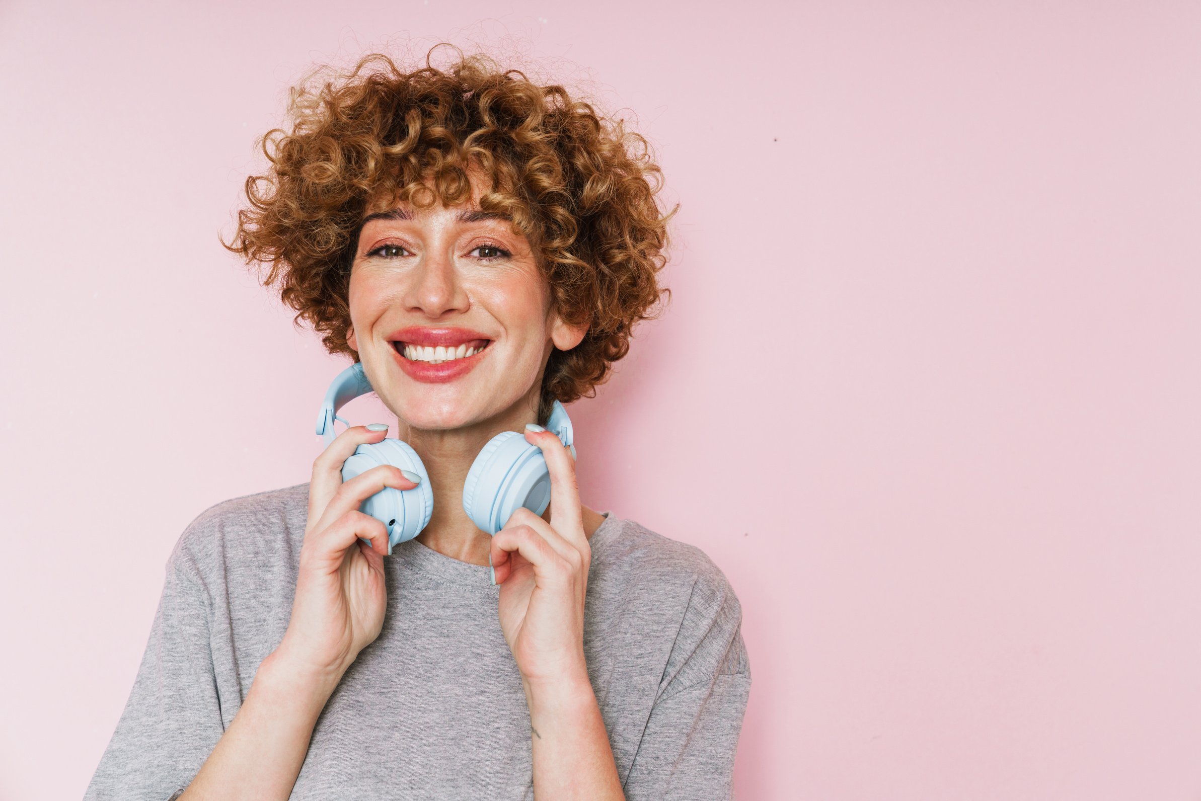 Cheerful Middle-Aged Woman Listening Music with Headphones Isolated